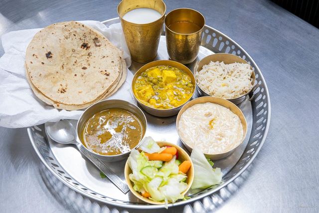 A langar thali — roti, dal, rice, kheer, salad and a steel tumbler