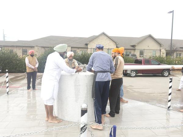 Washing the base of the Nishan Sahib during Nishan Sahib Sewa at Gurdwara Akaljot